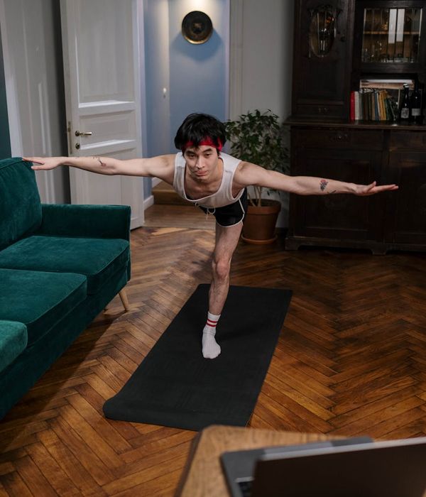 Person practicing gentle yoga poses in a dark indigo room